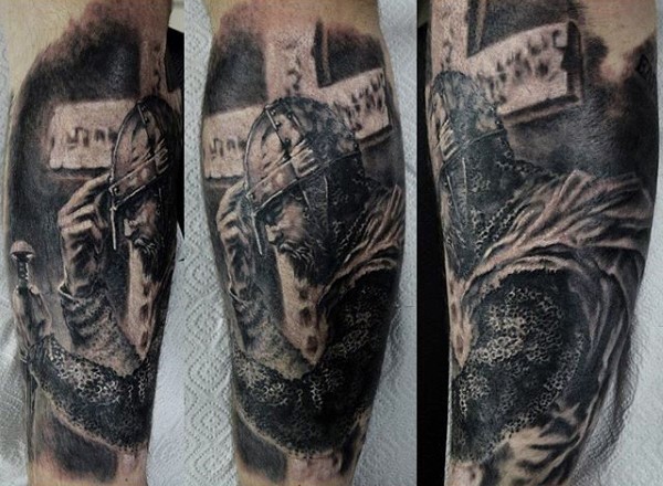 Accurate painted black ink praying medieval knight tattoo on forearm stylized with old cross