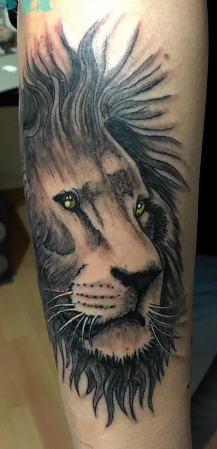 Tatuaggio colorato e preciso della testa di leone con grandi occhi gialli