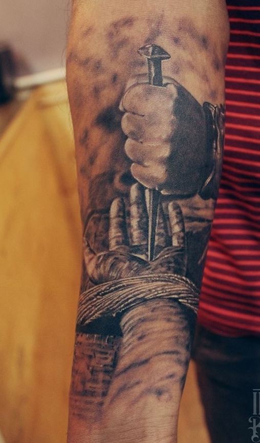 Tatuaje en el antebrazo,
mano de Jesús con clavo