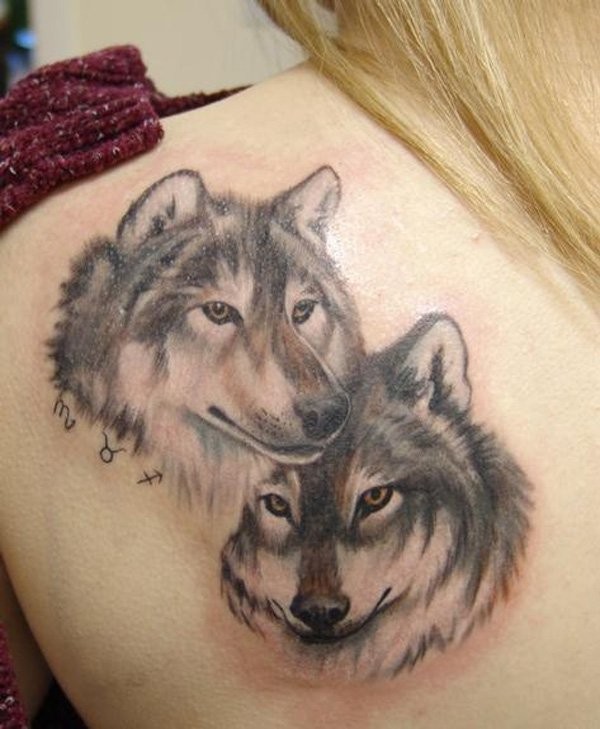 Impresionante tatuaje de la pareja de lobos con pequeños signos zodiacales en la espalda