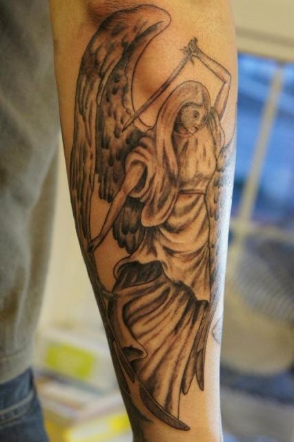 Tatuaje  de ángel con espada en el antebrazo