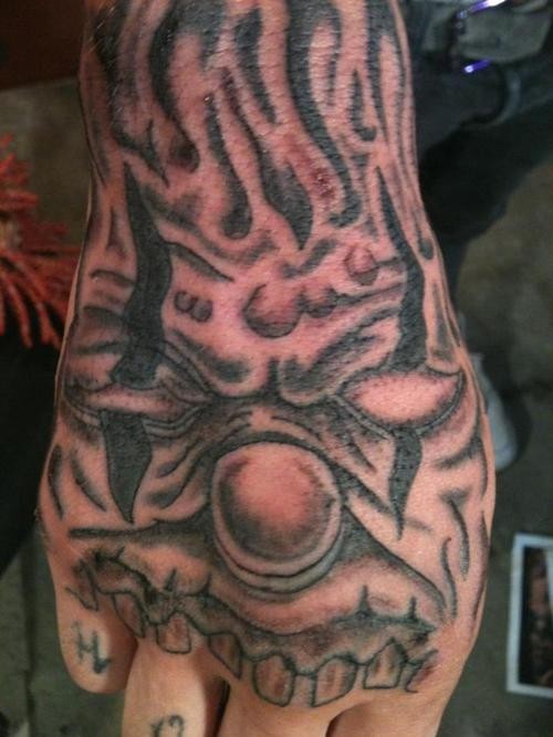 Angry clown face tattoo on hand
