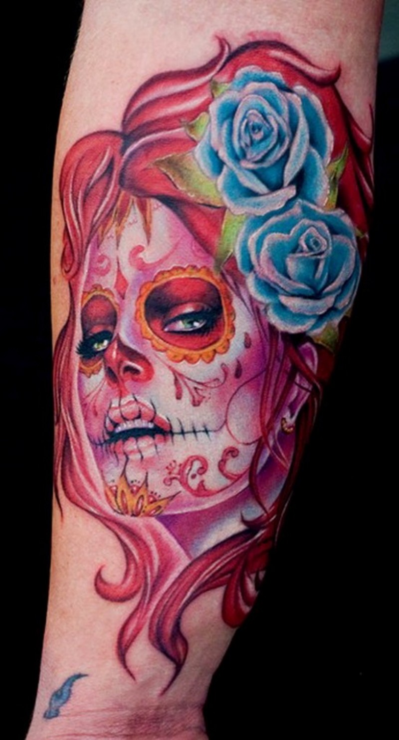 Tatuaje en el antebrazo,
santa muerte en colores rosas con dos rosas azules