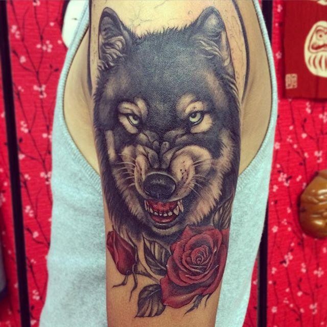 Art style beautiful looking upper arm tattoo of evil wolf with roses