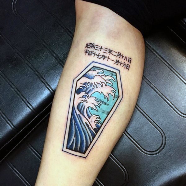 Tatuaje en el brazo, ataúd con olas dibujadas en la tapa y jeroglíficos