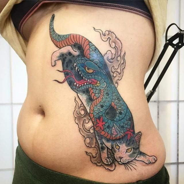 Tatuaggio laterale colorato in stile asiatico del gatto Manmon stilizzato con grande serpente grande
