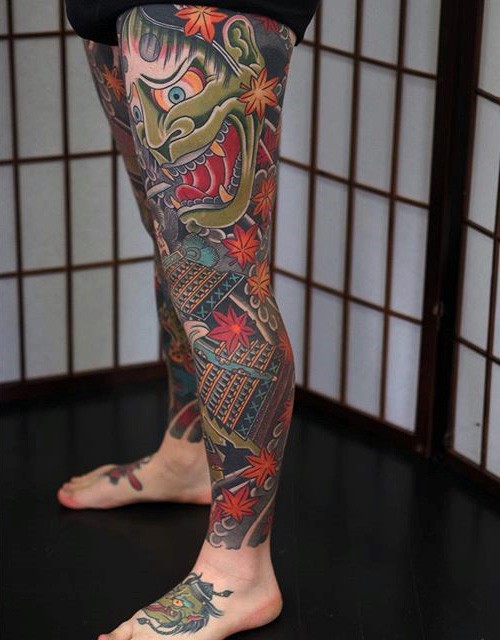 Asian style massive colorful tattoo on whole leg with demonic mask and samurai warrior