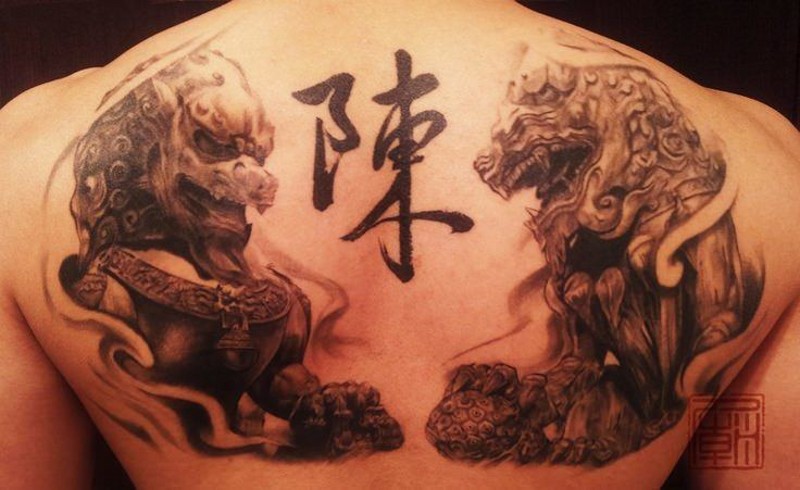 Asian traditional detailed upper back tattoo of lion statues with symbol