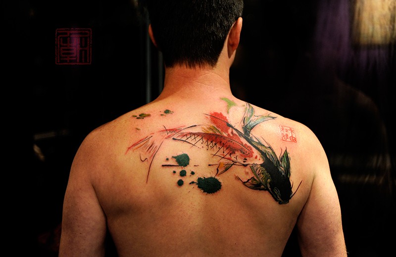 Asian traditional multicolored upper back tattoo of swimming carp fishes