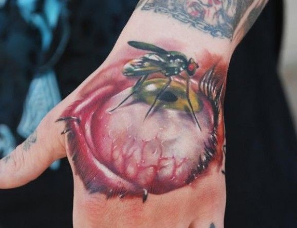 Tatuaje en la muñeca impresionante de un globo ocular realista en 3d con una mosca.