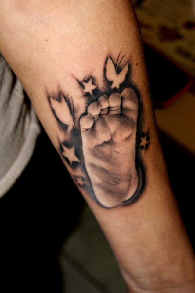 realistico piede di bambino con farfalle e stelle tatuaggio su braccio