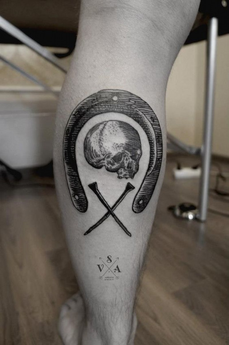 Awesome black ink horseshoe with skull and nails tattoo on leg