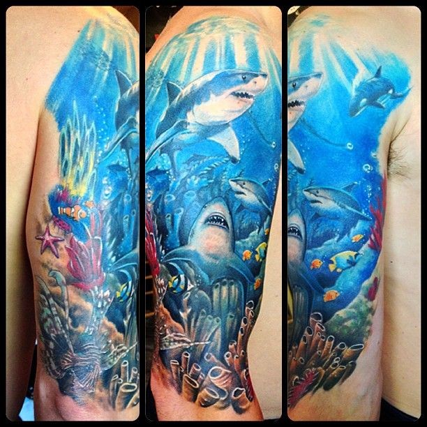Awesome bright multicolored ocean bottom full of sharks tattoo on man's shoulder in realism lifelike style