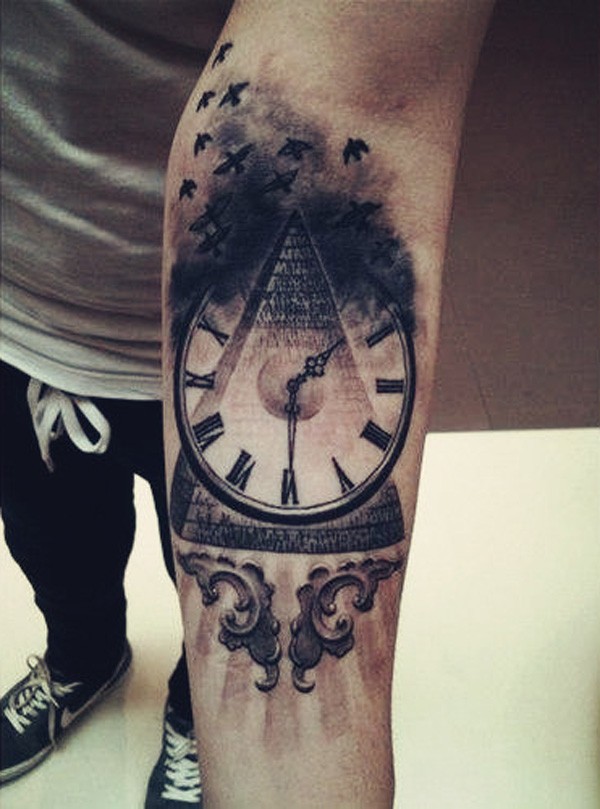 Tatuaje en el antebrazo, pirámide y reloj y bandada de aves