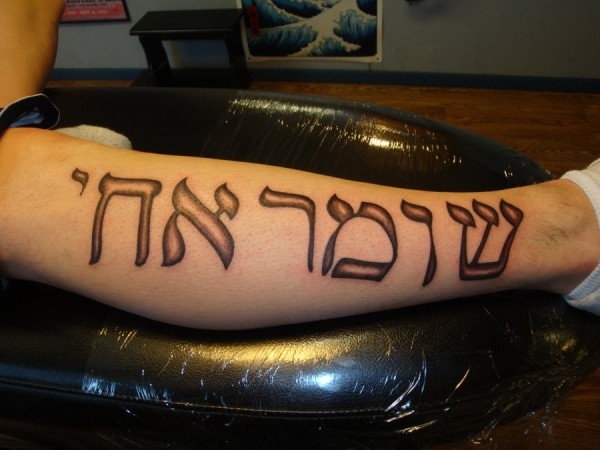 Tatuaje de escrito hebreo grande en la pierna