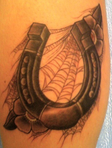 Awesome horseshoe with spider web and flowers tattoo