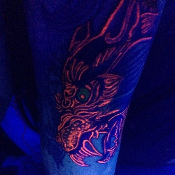 Awesome red glowing ink painted evil monster tattoo on arm