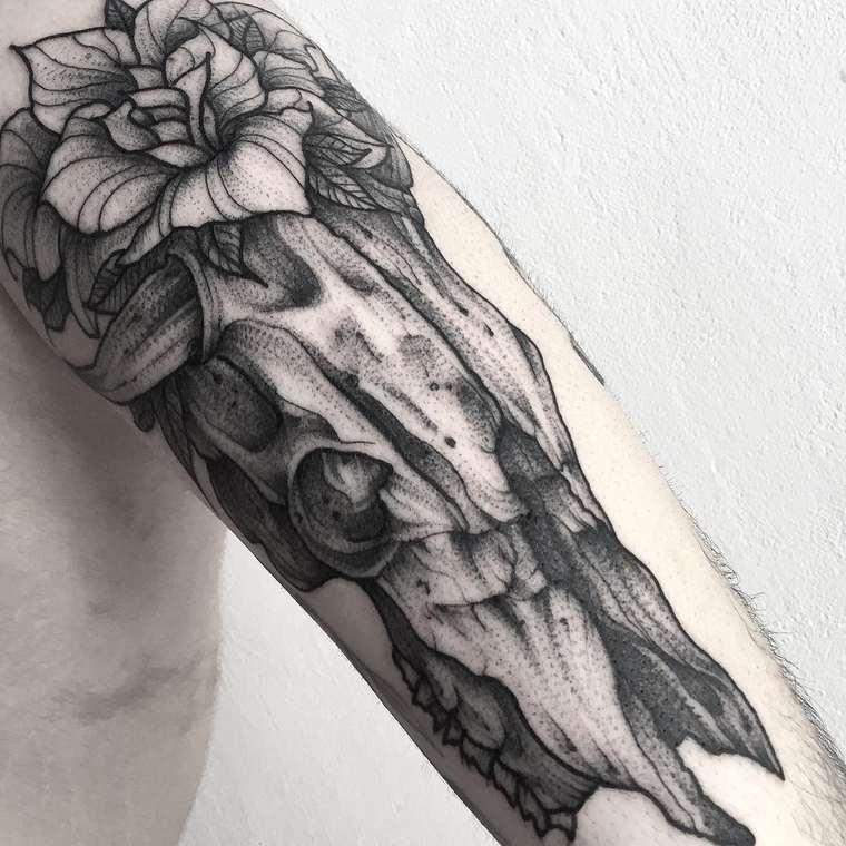 Tatuaje en el brazo,
cráneo realista 3D de animal con flor preciosa