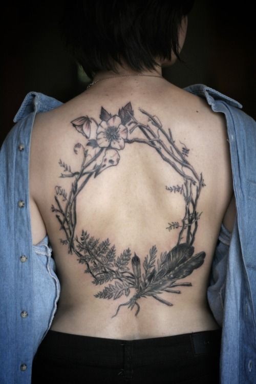 Tatuaje en la espalda, rama con hojas y flores secas