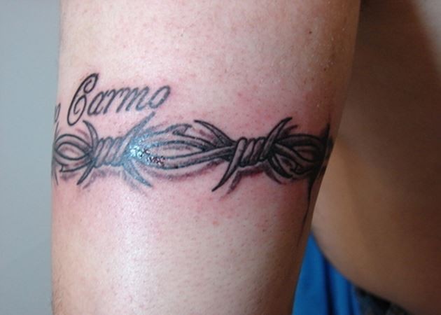 Barbed wire and name tattoo on arm