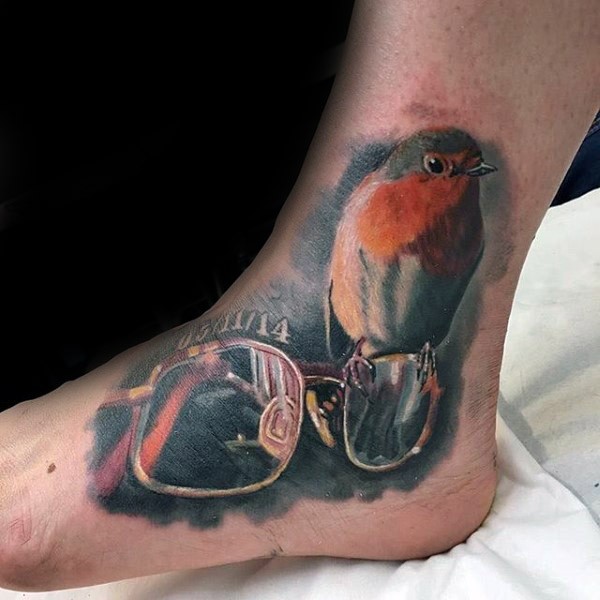 Beautiful 3D style colored ankle tattoo of glasses and small bird