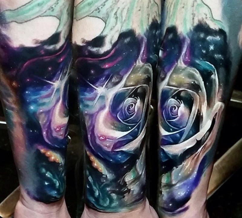 Beautiful colored little rose in space tattoo on arm