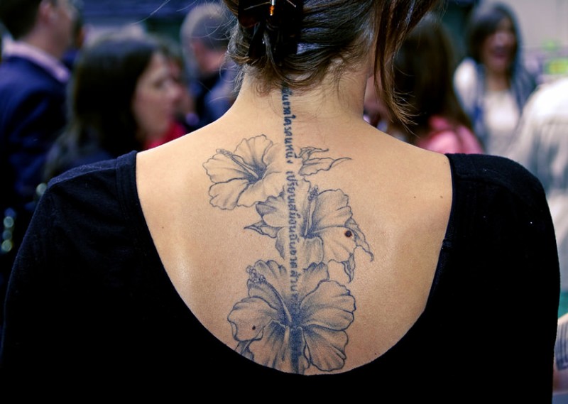 Beautiful hibiscus flowers and hebrew inscription tattoo on back