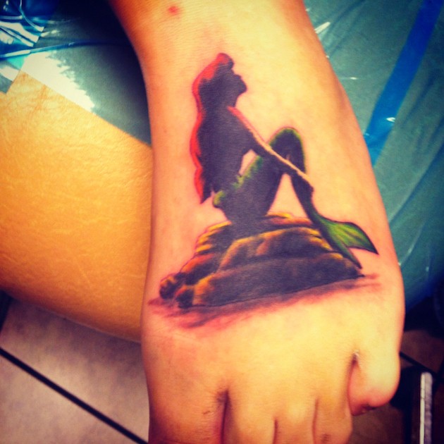 Tatuaje en el pie, silueta de sirena en la piedra