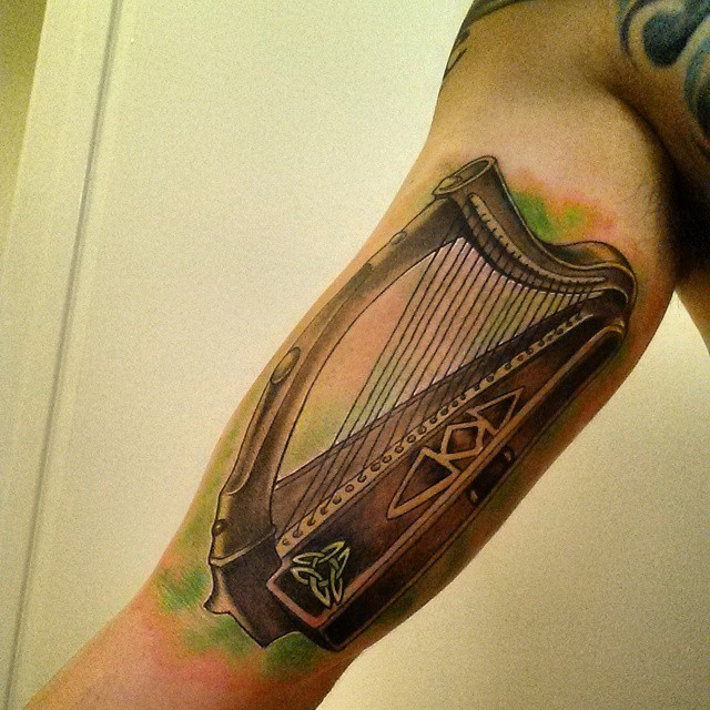 Beautiful looking colored arm tattoo of Celtic harp