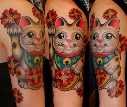 Beautiful looking colored shoulder tattoo of maneki neko japanese lucky cat statuette and red flowers