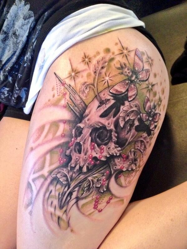 Beautiful looking colored thigh tattoo of human skull with butterflies