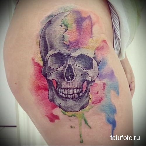 Beautiful looking colored thigh tattoo of large skull with paint