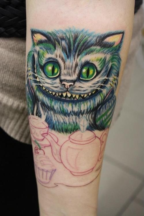 Tatuaje en el antebrazo,
gato de Cheshire sonriente adorable con taza de té y magdalena