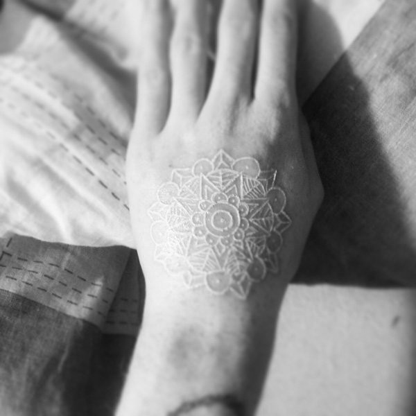Tatuaje en la mano, mandala preciosa de tinta blanca