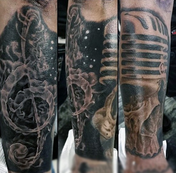 Big and mystical black ink skull with microphone tattoo on leg