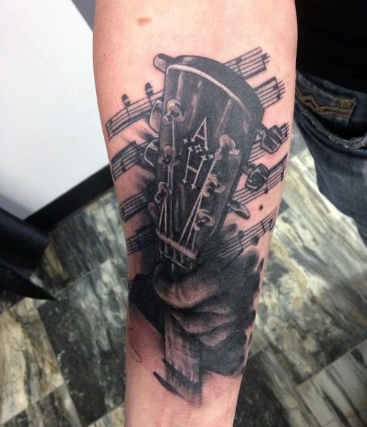 Big black and white guitar with notes tattoo on arm