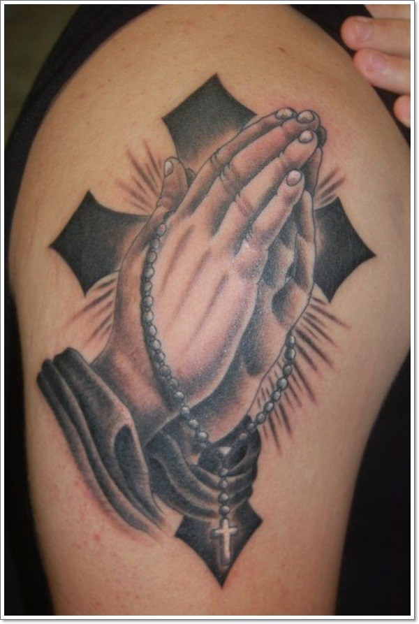 Big black ink cross with praying hands tattoo on upper arm