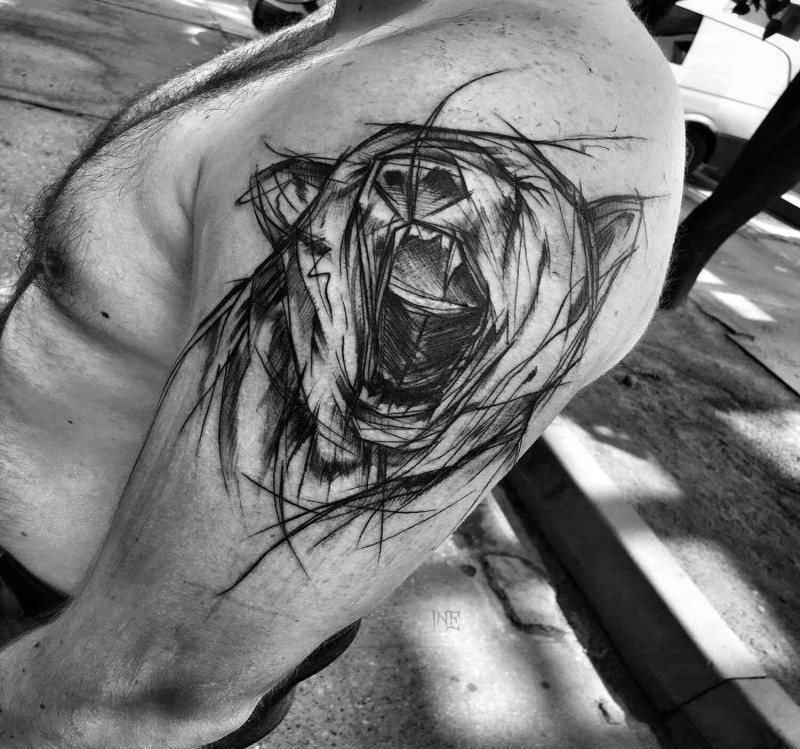 Tinta preta grande pintada por Inez Janiak tatuagem do braço do urso rugindo