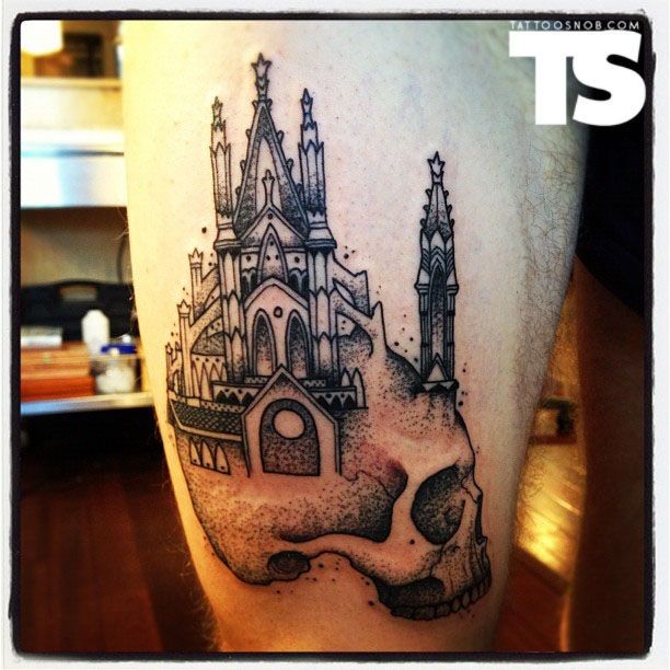 Big black ink thigh tattoo of human skull with big castle