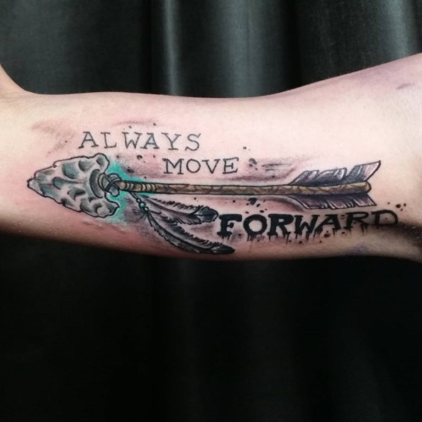 Big colored ancient tribal arrow tattoo on biceps with &quotAlways move forward" lettering