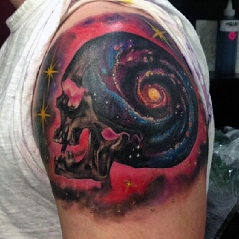 Tatuaje en el brazo,
cráneo multicolor con galaxia