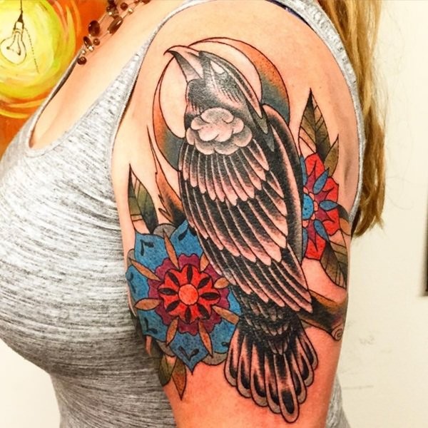 Tatuaje en el hombro, cuervo oscuro con flores vistosas