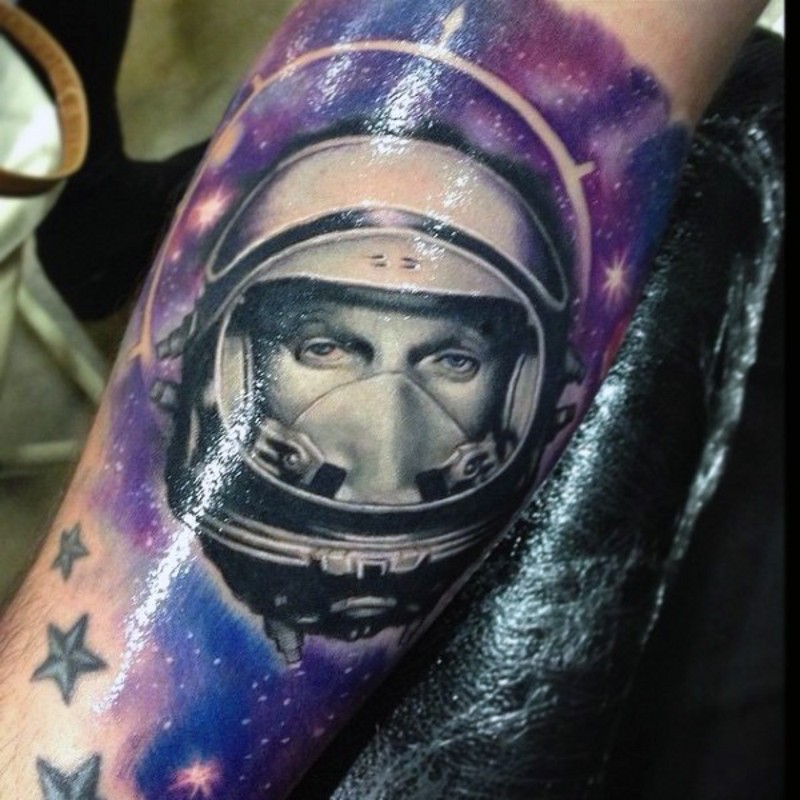 Tatuaje en el antebrazo,
cara de astronauta realista en cosmos pintoresco