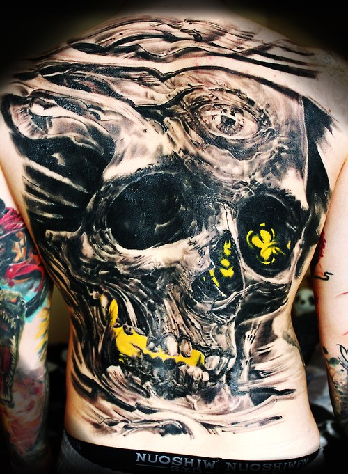 Big horrendous  black skull tattoo on back