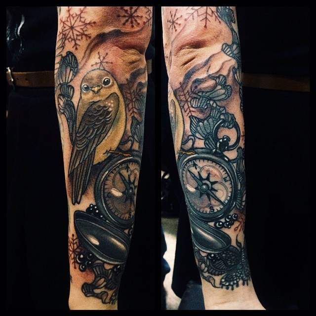 Big illustrative style colored forearm tattoo of bird with compass