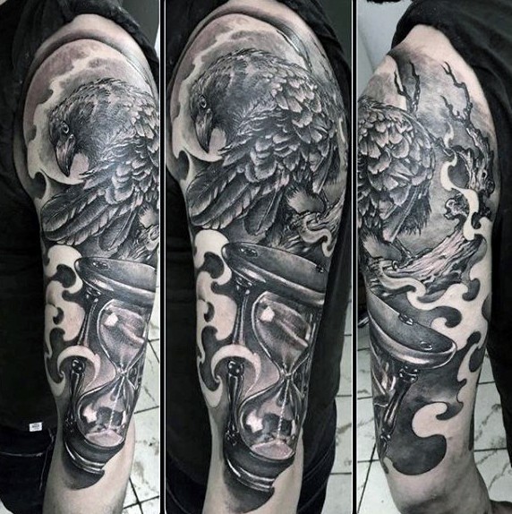 Big mystical themed black ink tattoo with crow and sand clock tattoo on half sleeve area