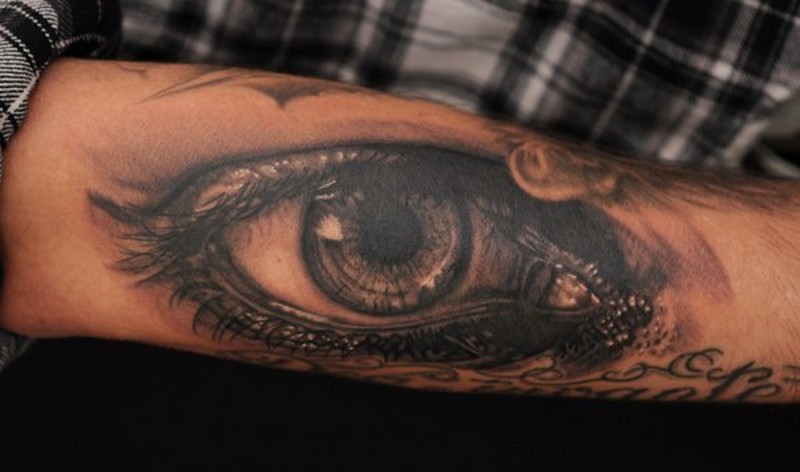 Großes natürlich aussehendes schwarzes und weißes trauriges Auge Tattoo am Arm