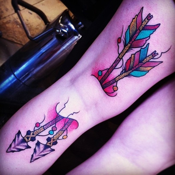 Big old school designed ancient arrows tattoo on forearm stylized with colorful feather