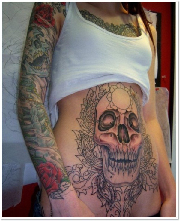 Big skull with black patterns tattoo on stomach