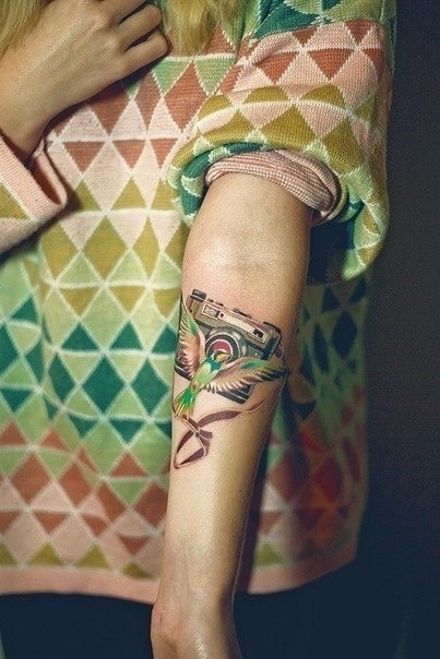 Bird and photo camera tattoo on arm
